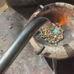 Melting gold casting grain with a torch in preparation of casting jewelry.