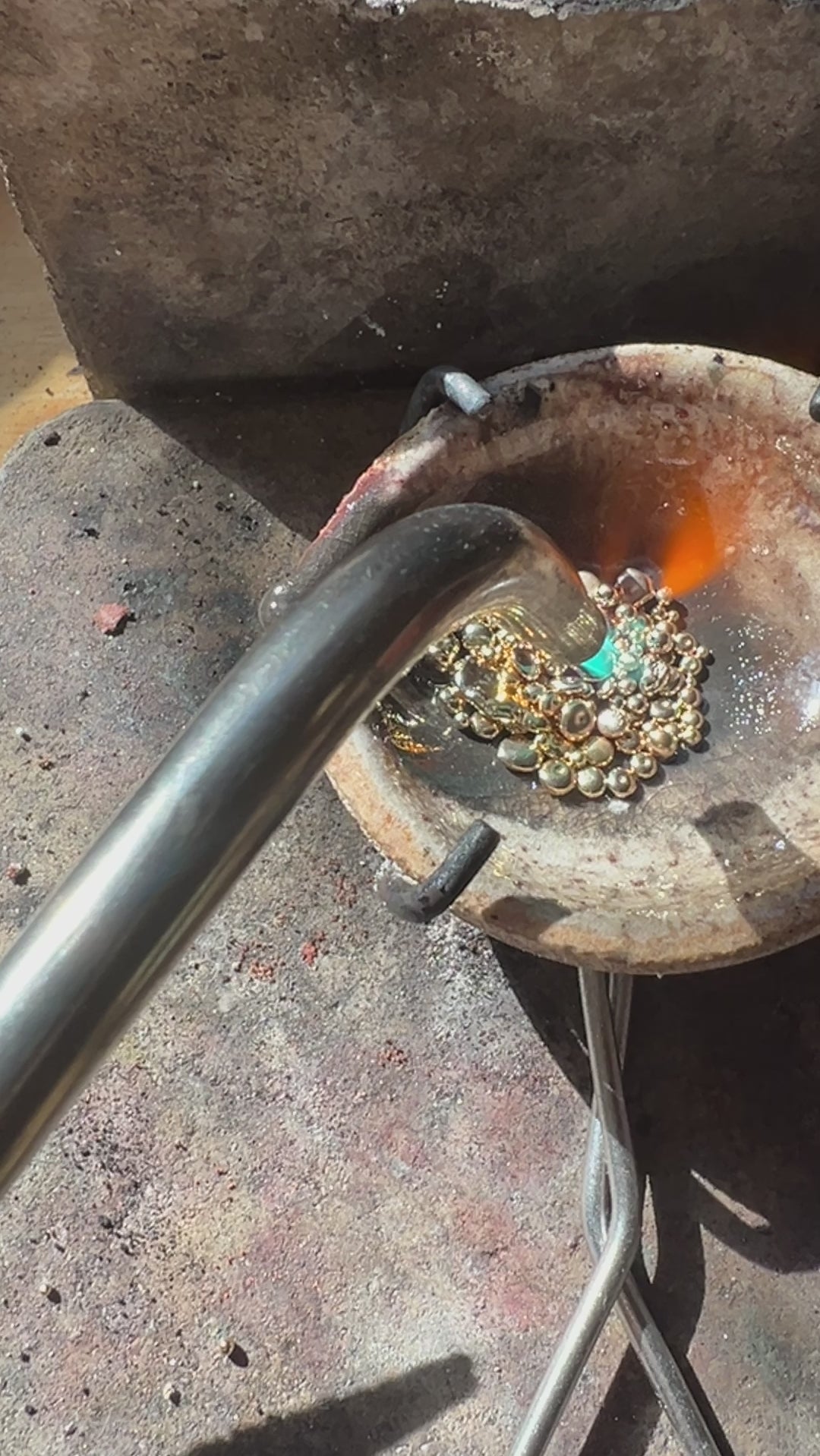 Melting gold casting grain with a torch in preparation of casting jewelry.